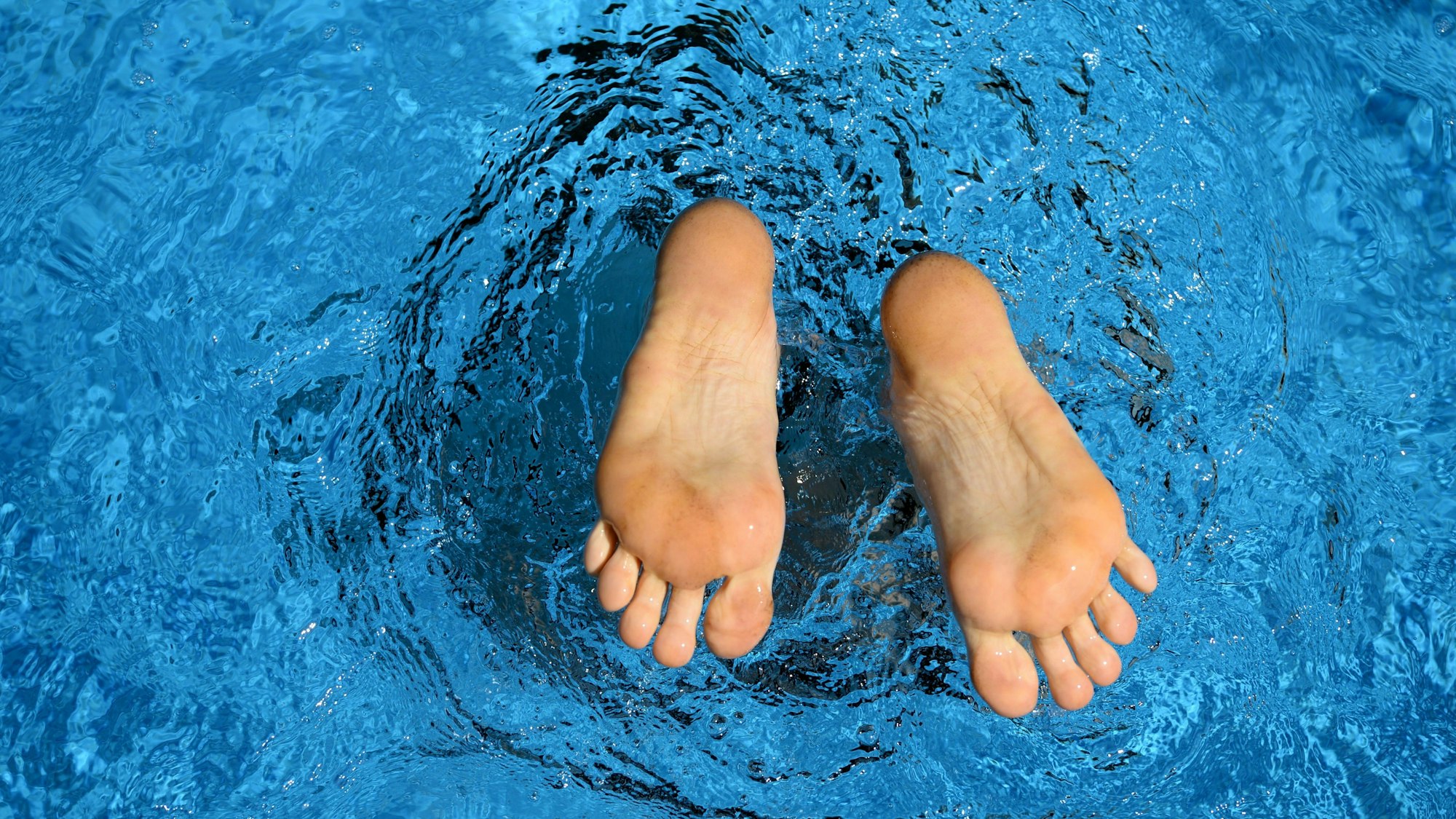 Die Füße eines Menschen schauen aus dem Wasser eines privaten Pools