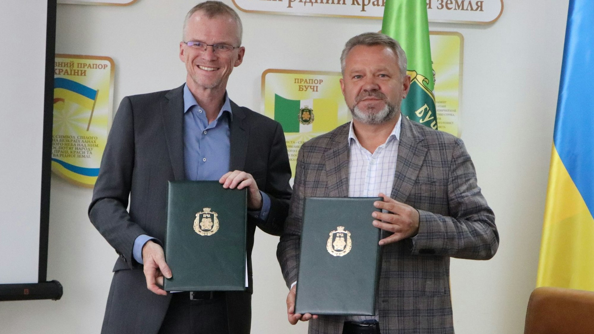 Bergisch Gladbachs Bürgermeister Frank Stein und Butschas Bürgermeister  Anatolii Fedoruk halten Mappen mit der unterschrieben Städtepartnerschaftsurkunde in den Händen.