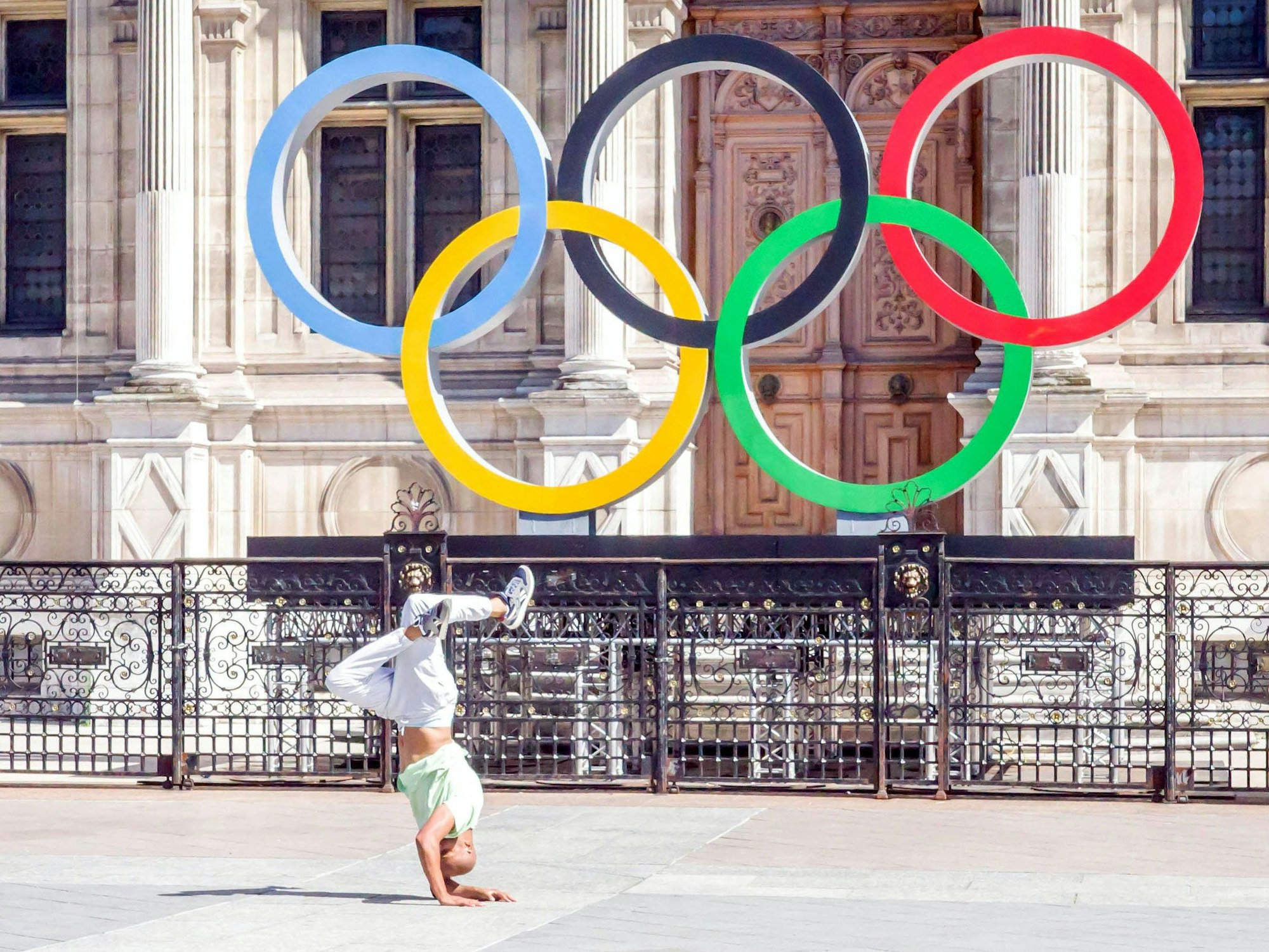 Ein Breakdancer tanzt vor den Olympischen Ringen am Rathaus von Paris.