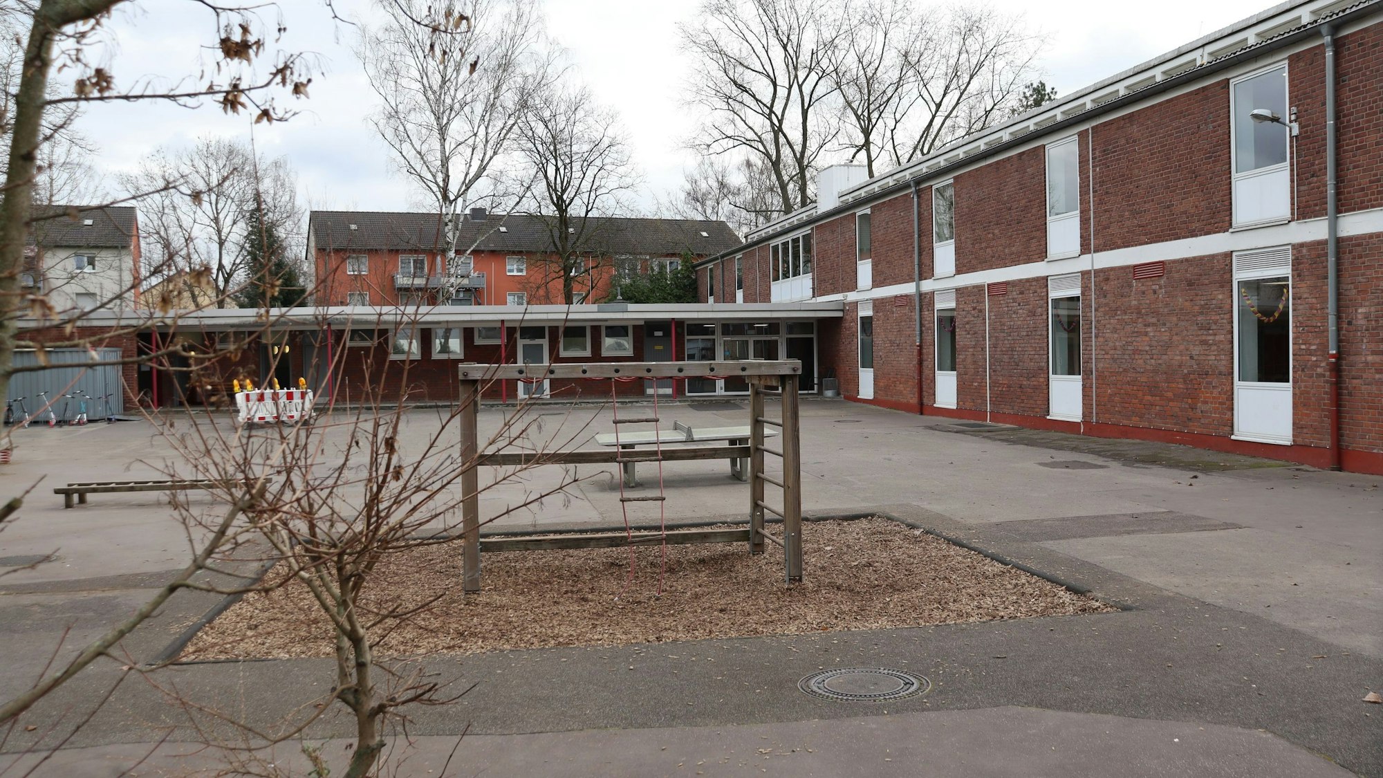 Blick auf einen Schulhof mit Spielgeräten und ein Schulgebäude