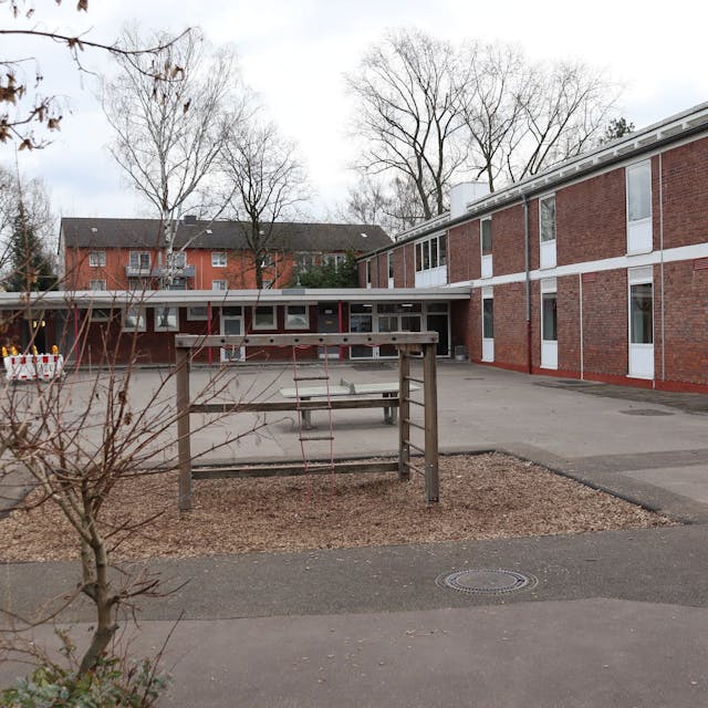 Blick auf einen Schulhof mit Spielgeräten und ein Schulgebäude