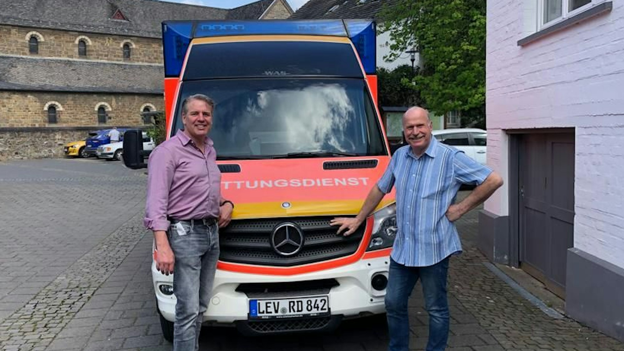 Odenthals Bürgermeister Robert Lennerts (links) und Gerd Kortschlag (Awo) stehen vor einem Rettungswagen in Odenthal.