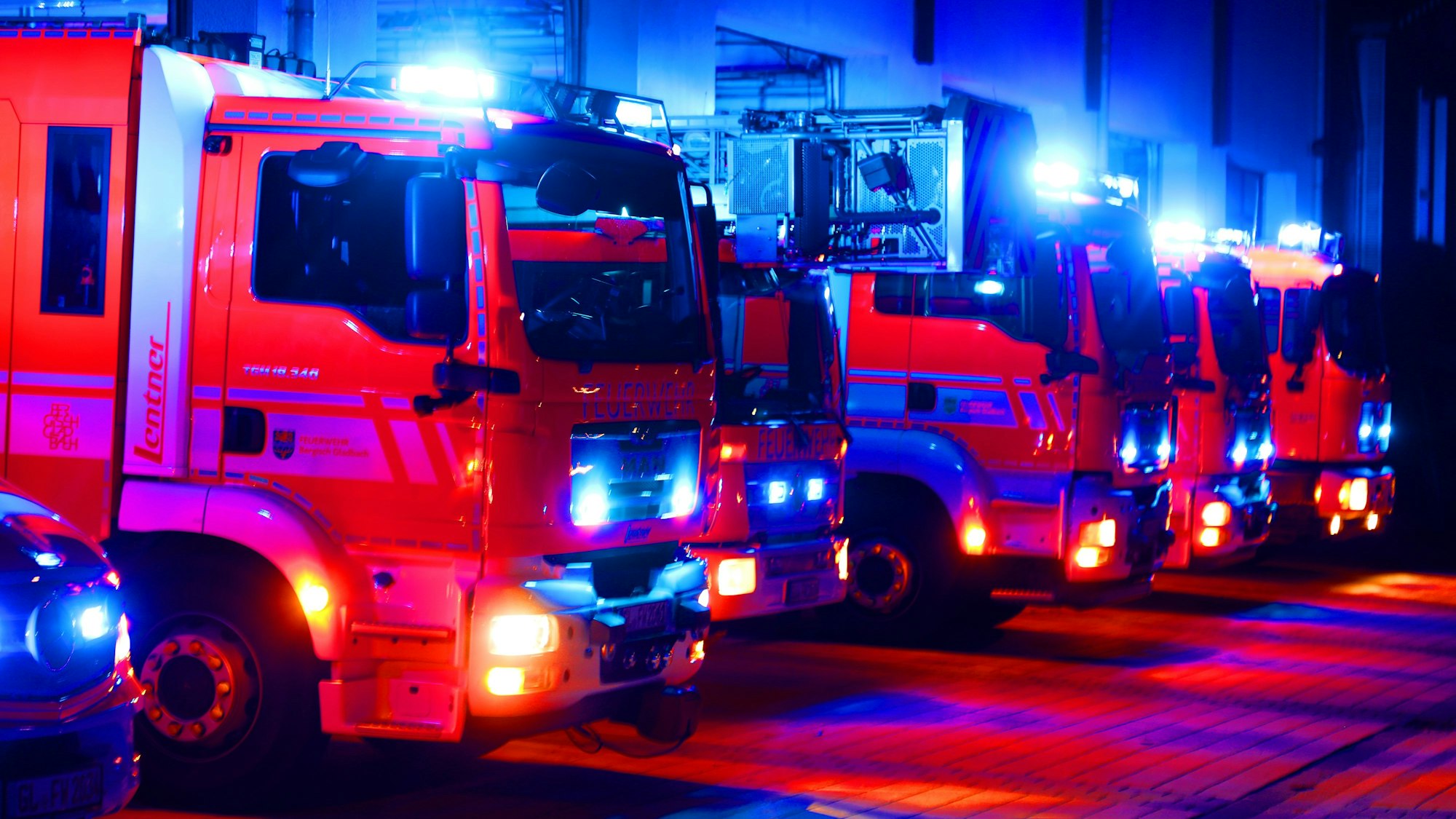 Feuerwehrfahrzeuge mit Blaulicht und Warnblinklicht stehen vor der Feuerwache an der Paffrather Straße in Bergisch Gladbach.