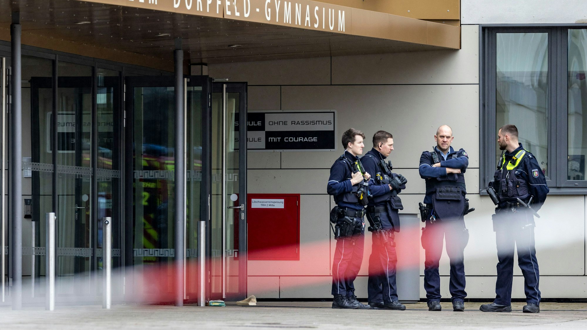 Polizeibeamte stehen vor dem Wilhelm-Dörpfeld-Gymnasium. In Wuppertal sind an einem Gymnasium mehrere Schüler verletzt worden. Ein Verdächtiger sei festgenommen worden, sagte ein Polizeisprecher in Düsseldorf.