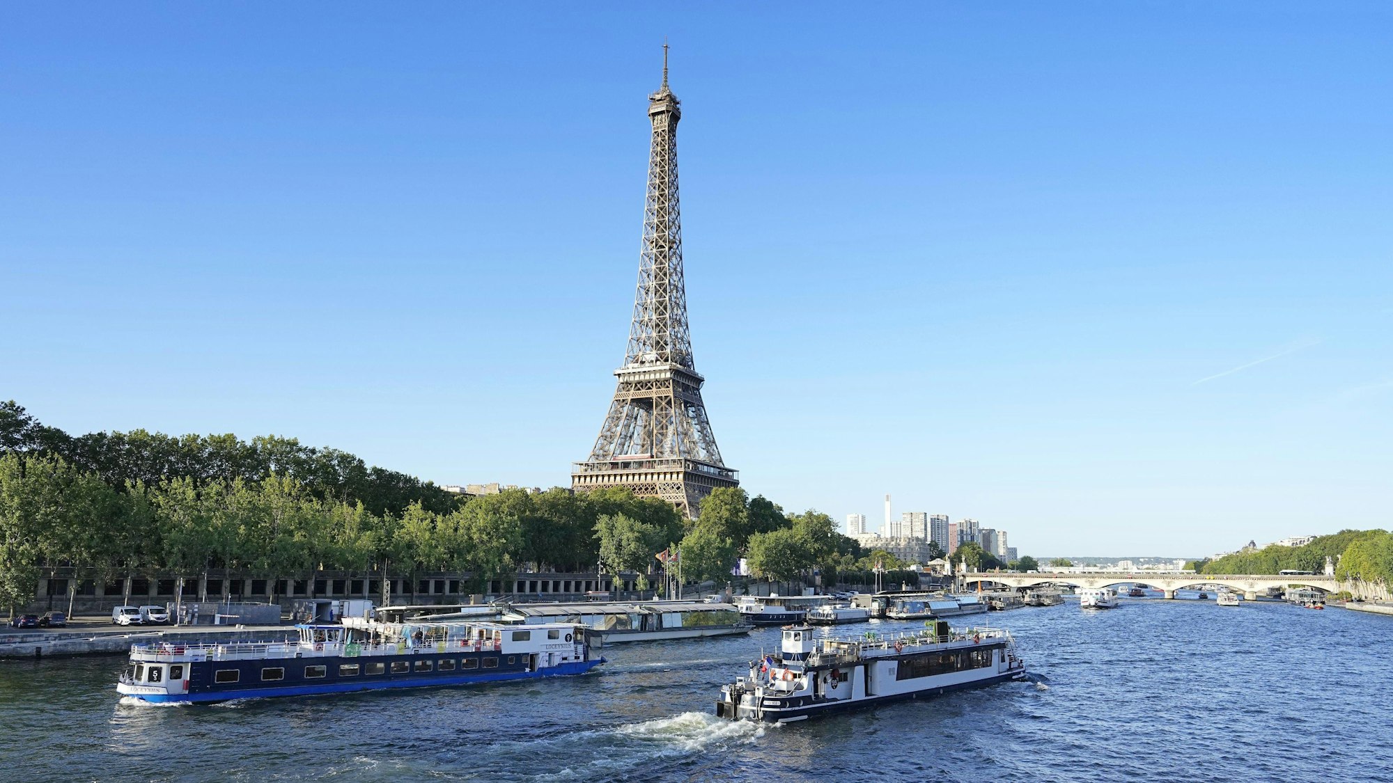 Ein Boot und ein Lastkahn fahren vor dem Eiffelturm auf der Seine während eines Tests für die Eröffnungsfeier der Olympischen Spiele 2024 in Paris.