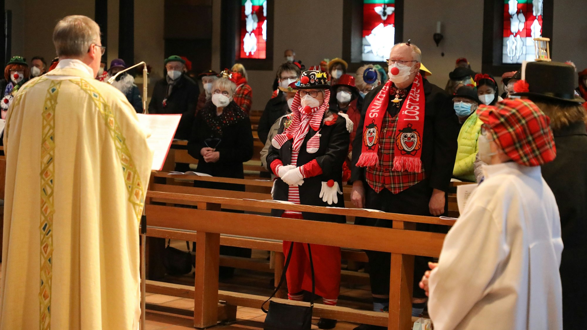 Pfarrer Wilhelm Darscheid predigt vor kostümierten und mit FFP2-Maske ausgestatteten Karnevalisten in der Möhnemess in Bergisch Gladbach Schildgen am 24. Februar 2022.