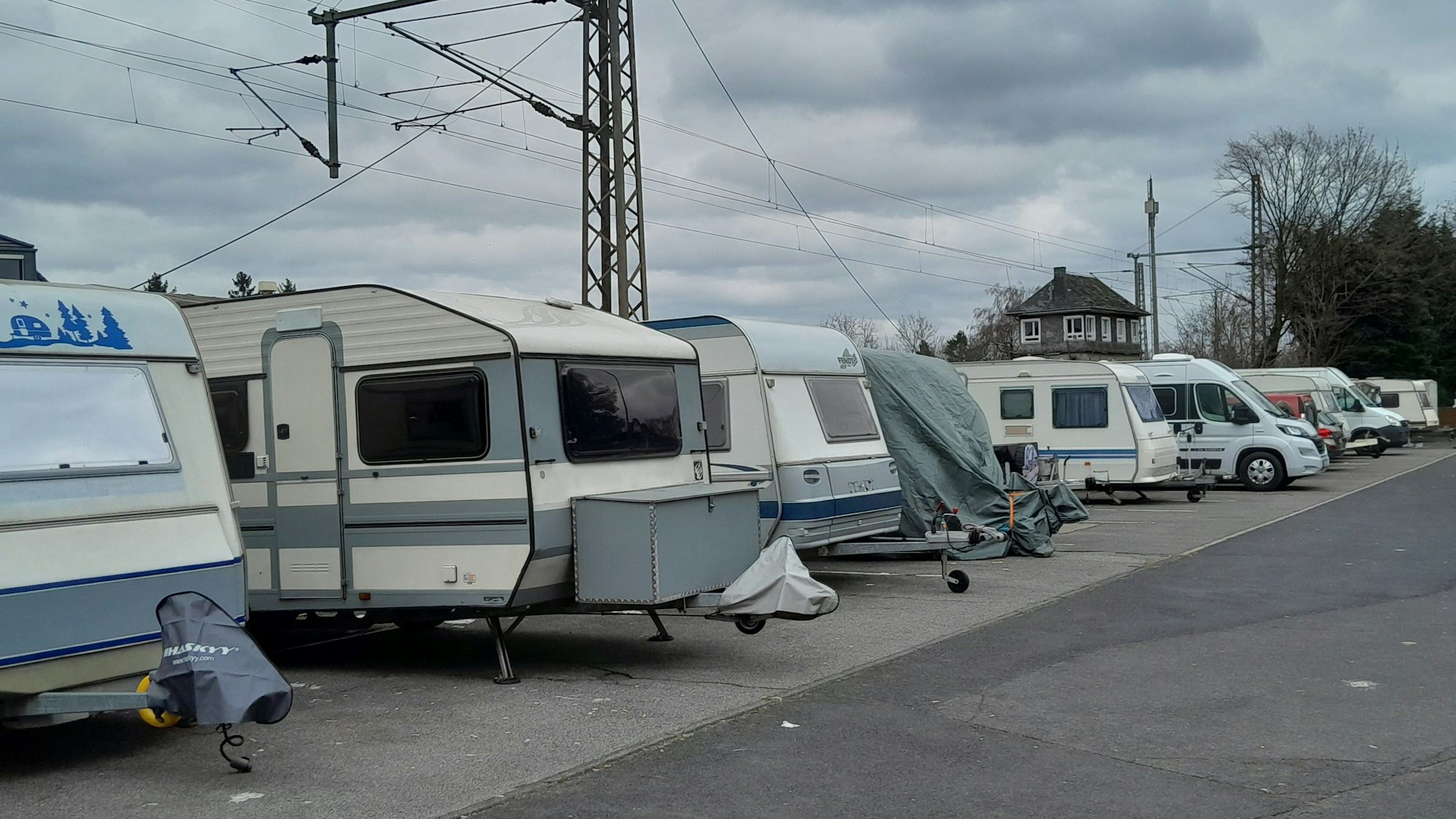Wohnwagen und Campingmobile stehen dicht an dicht auf einem Parkplatz.