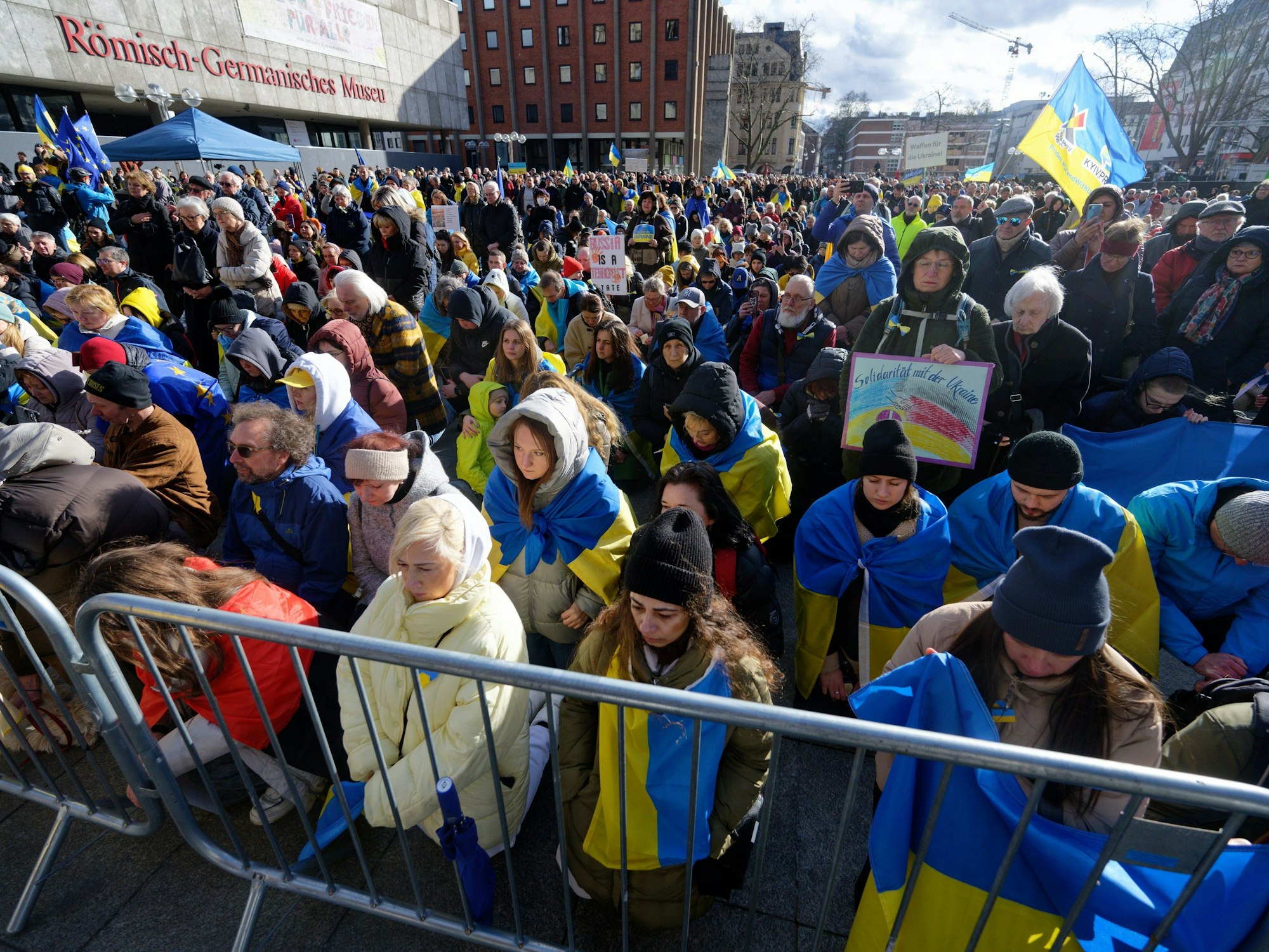Teilnehmer einer Kundgebung anlässlich des zweiten Jahrestages des Krieges in der Ukraine halten eine Schweigeminute ab.
