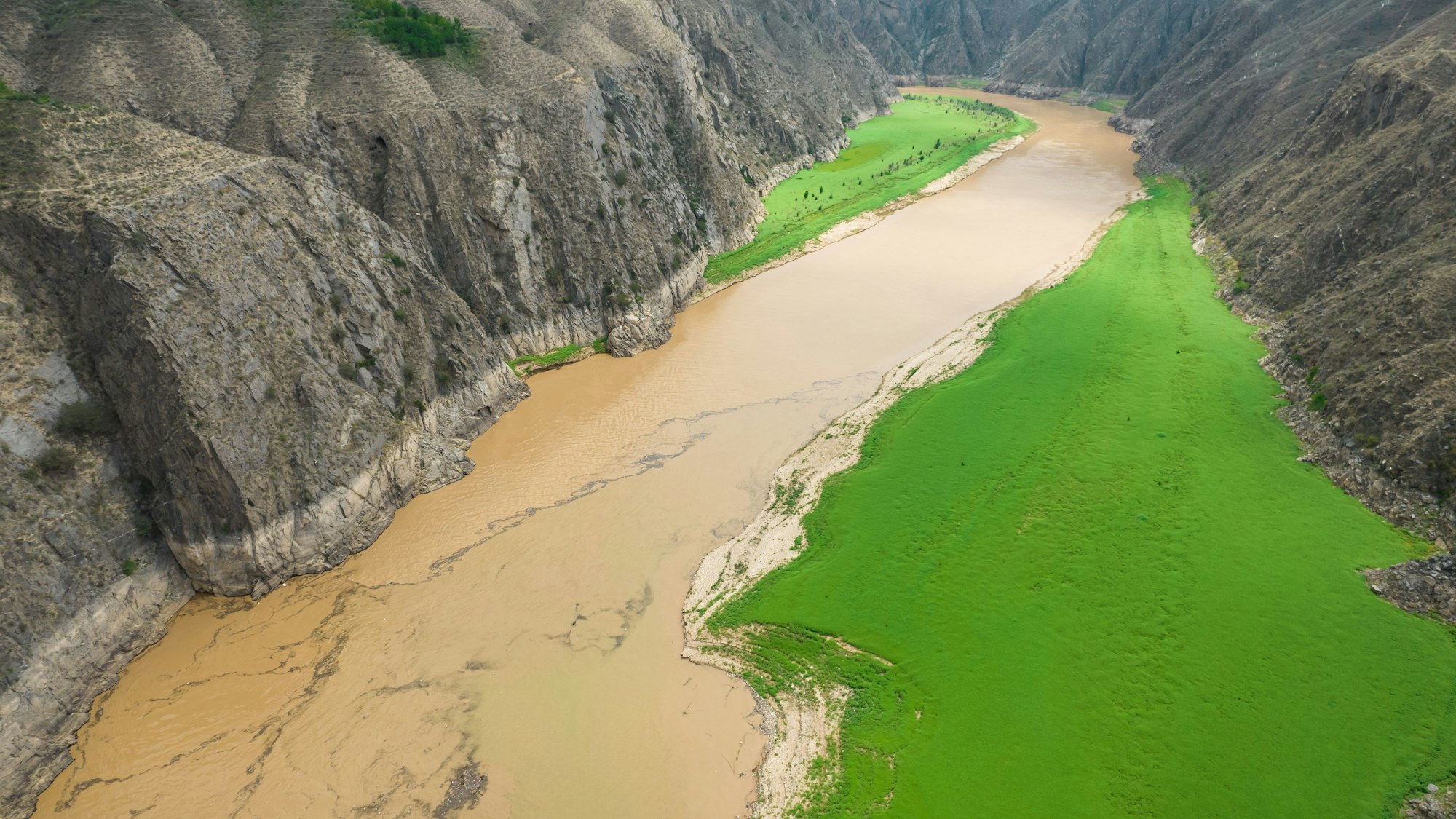 Die Farbe des Huang He (Gelber Fluss) ändert sich von grün zu gelb an der Mündung des Tao-Flusses.