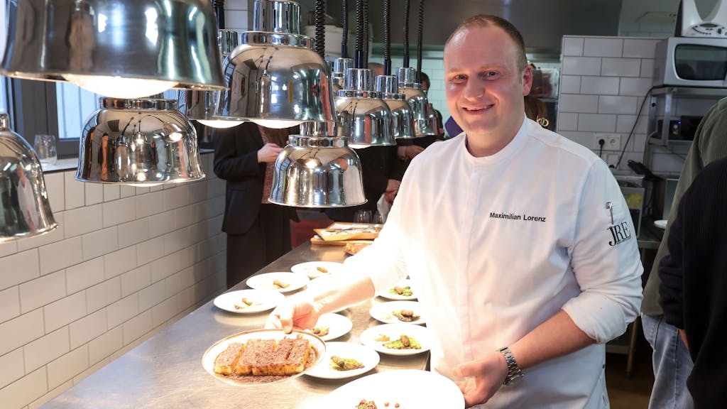 Koch Maximilian Lorenz hält zwei Teller mit Sauerbraten in seiner Restaurantküche in die Kamera.