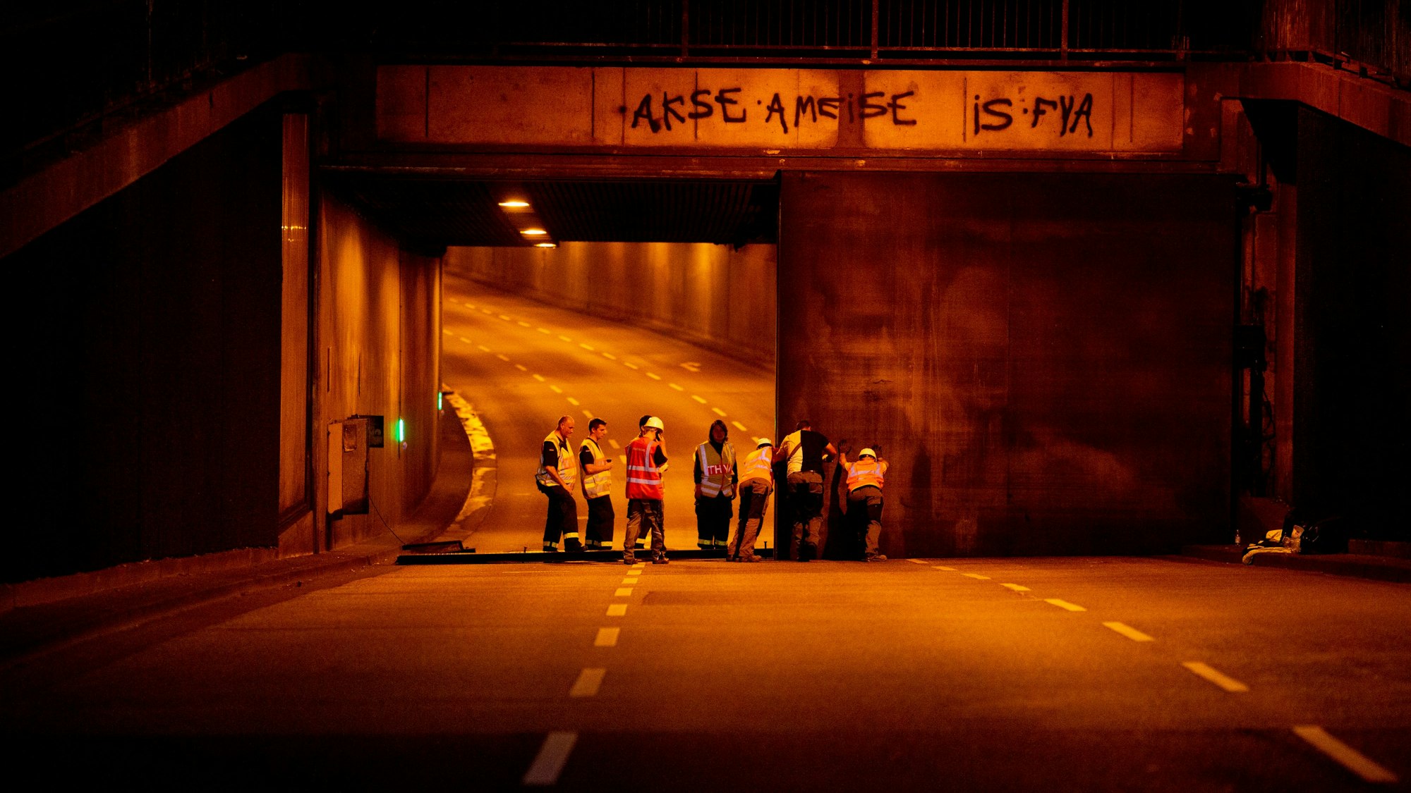 Mehrere Männer arbeiten in der Nacht an einem Tunnel und bringen Schutzwände an.