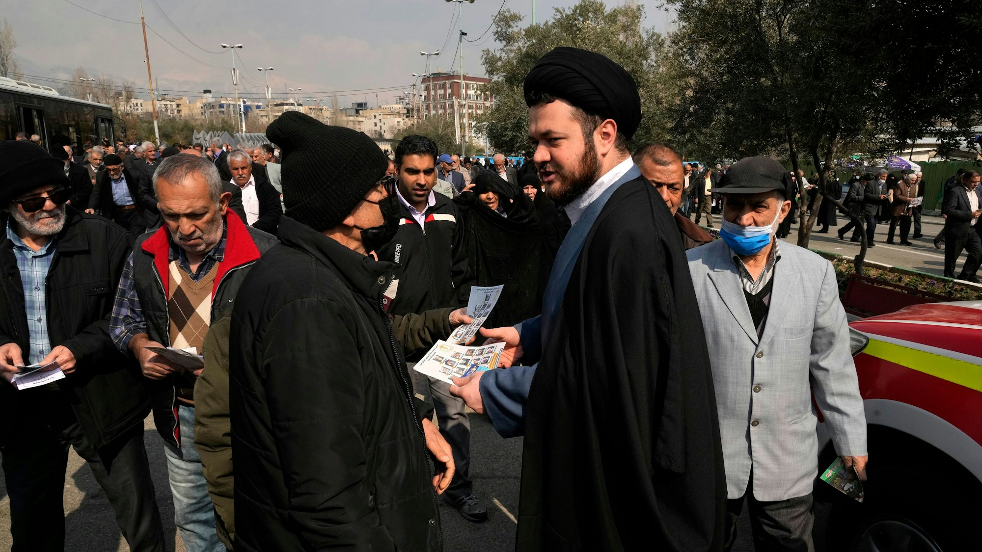 23.02.2024, Iran, Teheran: Ein Geistlicher verteilt Wahlprospekte einer Gruppe von Kandidaten für die Wahl des Expertenrates. Am 1. März wählt der Iran ein neues Parlament und den sogenannten Expertenrat.