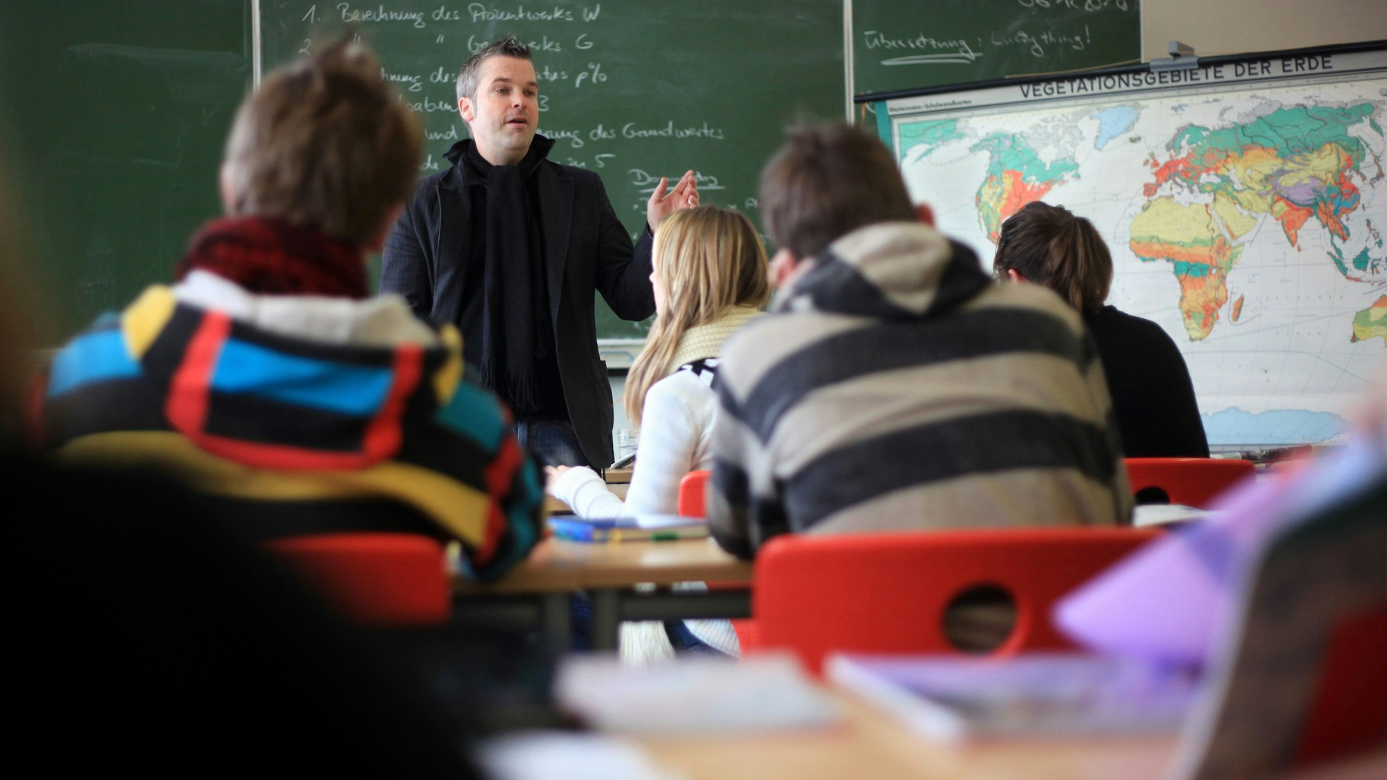 Ein Lehrer unterrichtet eine Schulklasse vor einer Tafel.