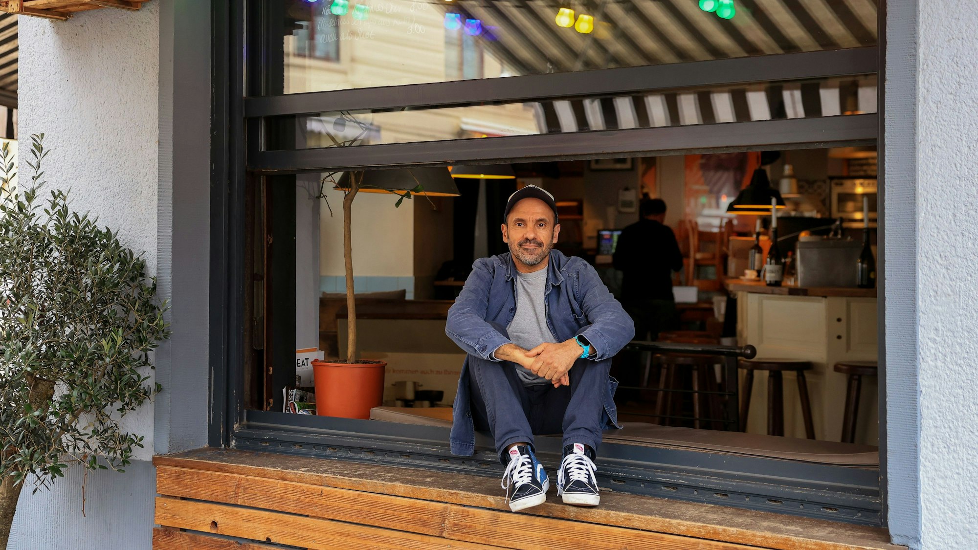 Der Inhaber des Meister-Gerhard Manuel Bouhaddouz sitzt vor seinem Restaurant auf der Fensterbank.