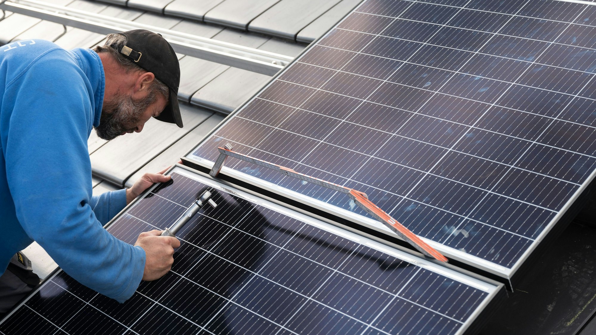 Ein Mann montiert eine Photovoltaikanlage.
