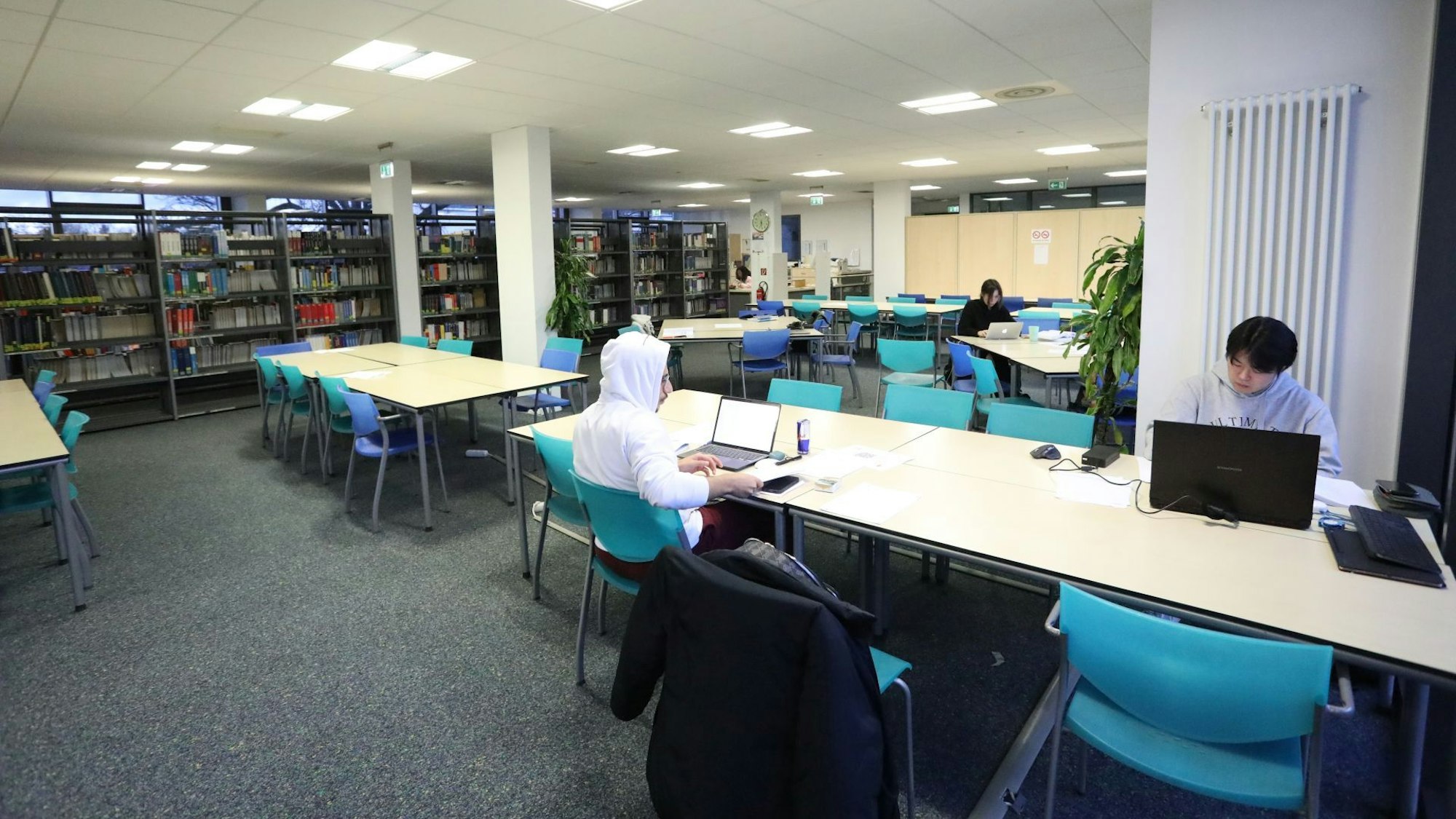Blick in eine Bibliothek an der Studenten an Tischen lernen. Zurzeit wird dieser Raum noch von der Hochschule genutzt, in der Freiraumschule wird er Treffpunkt zum Unterrichtsbeginn sein.