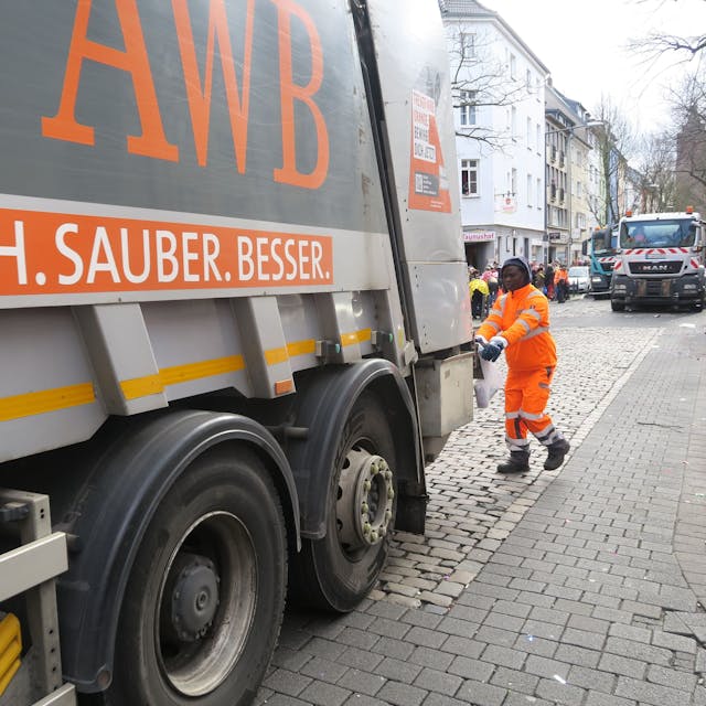 Ein Müllwagen der Abfallwirtschaftsbetriebe Köln steht auf einer Straße.