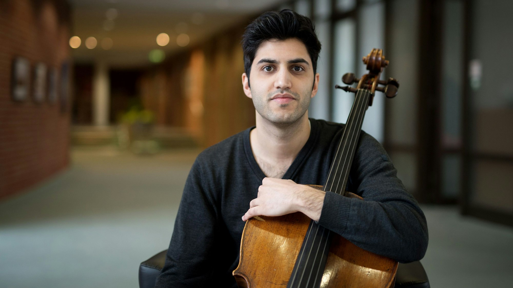 Der österreichisch-iranische Cellist Kian Soltani blickt in die Kamera. Er hält sein Cello mit einem