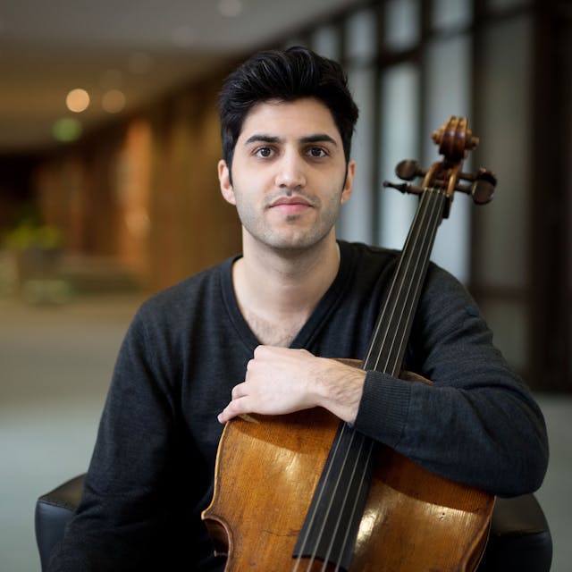 Der österreichisch-iranische Cellist Kian Soltani blickt in die Kamera. Er hält sein Cello mit einem&nbsp;