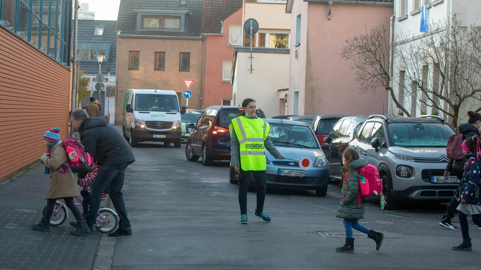Eine Schülerlotsin steht auf einer Straße und stoppt Autos.