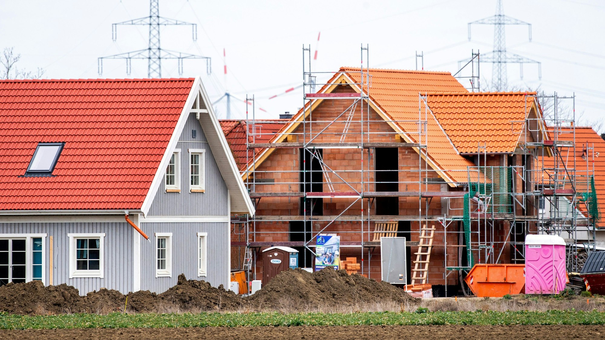 Mehrere im Bau befindliche Einfamilienhäuser stehen in einem Neubaugebiet.