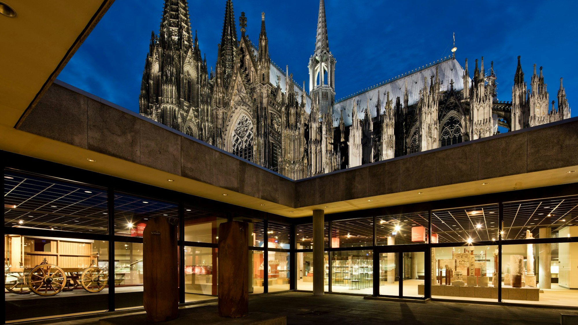 Über dem Atrium des Kölner Römisch-Germanischen Museums erhebt sich der angestrahlte Dom.