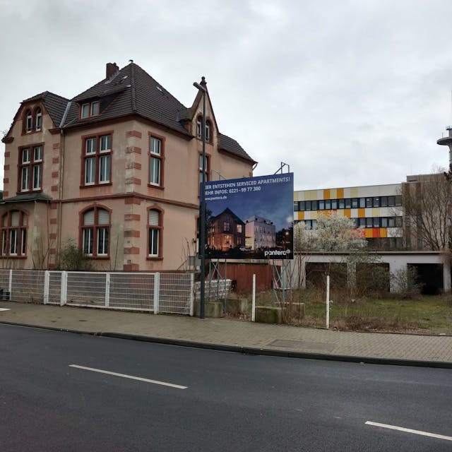 Ein Plakat kündigt neben einem alten Gebäude ein Bauprojekt an.