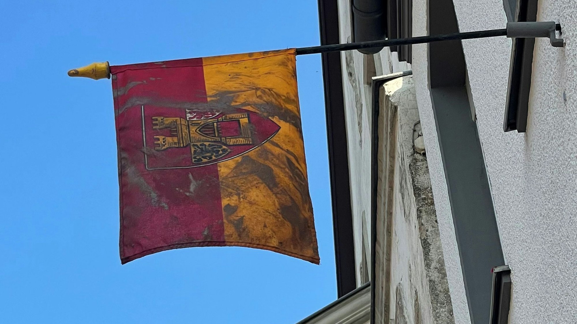 Das Bild zeigt eine Euskirchen-Fahne, die an einem Haus in Euskirchen hängt. Sie ist mit Flutschlamm verdreckt.
