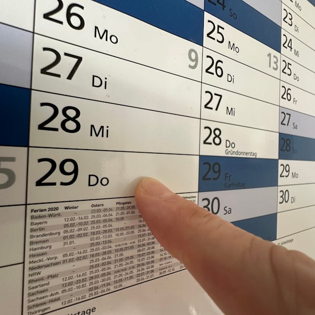 Ein Finger zeigt auf einen Kalender.