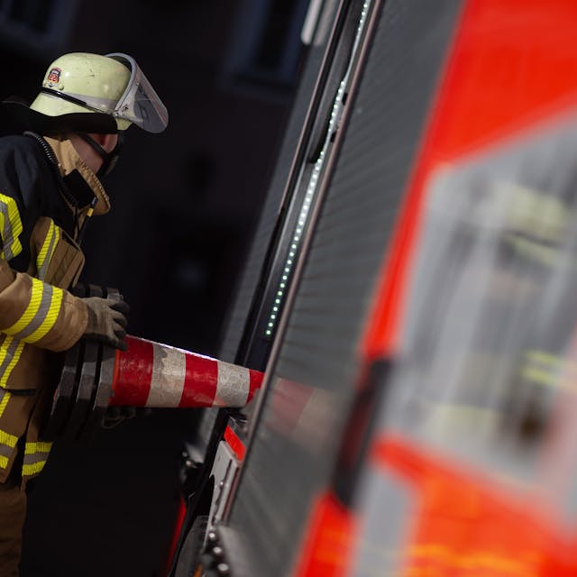 Eine Einsatzkraft der Feuerwehr nimmt eine Pylone aus einem Einsatzfahrzeug der Feuerwehr&nbsp;