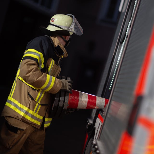 Eine Einsatzkraft der Feuerwehr nimmt eine Pylone aus einem Einsatzfahrzeug der Feuerwehr&nbsp;