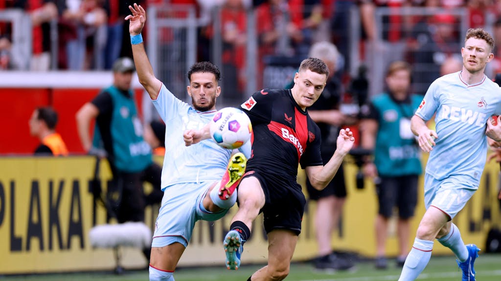 Leart Pacarada und Florian Wirtz beim Spiel zwischen Bayer Leverkusen und dem 1. FC Köln im Duell um den Ball.
