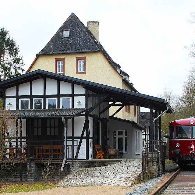 Neben dem Gebäude des Museumsbanhnhofs steht ein roter Schienenbus auf den Gleisen.