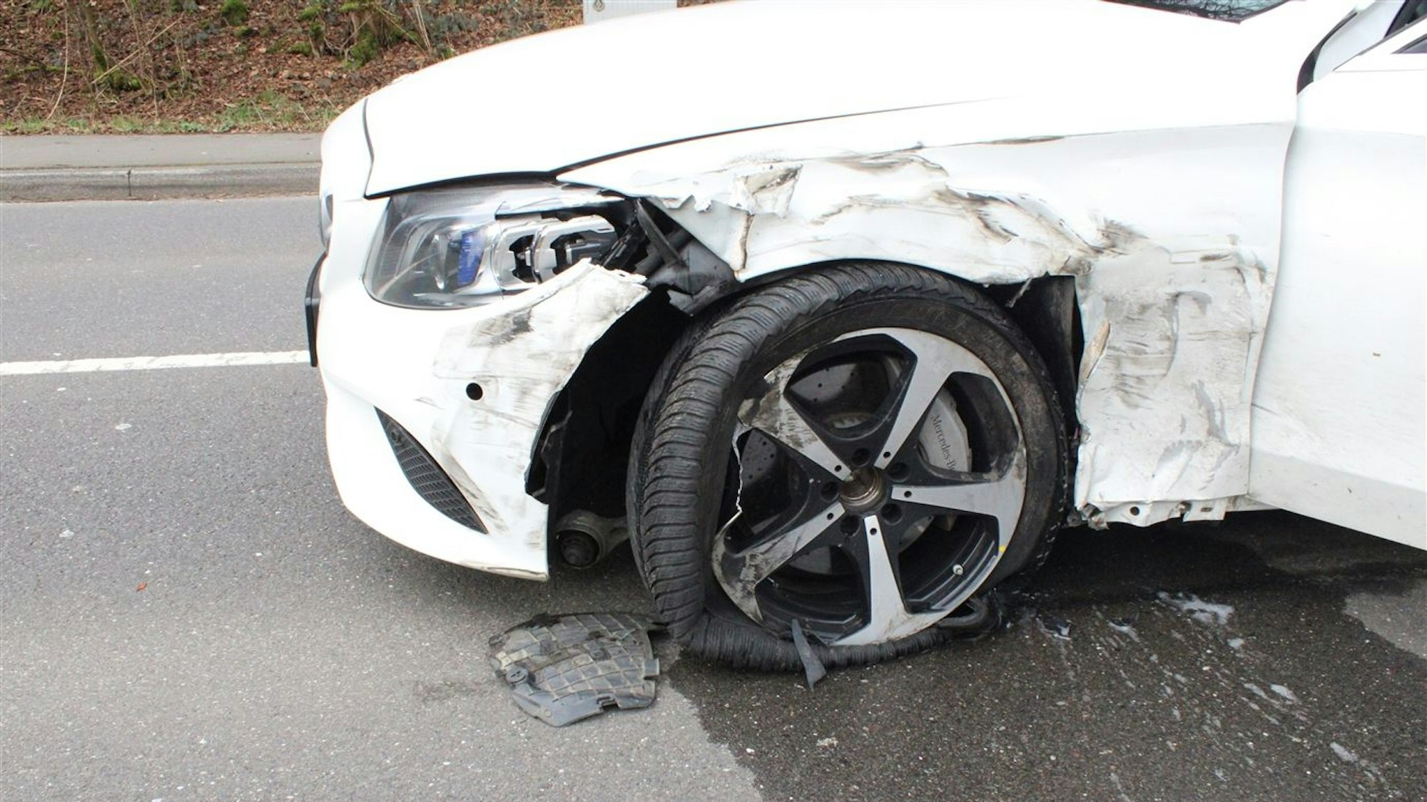 Ein weißer Mercedes hat nach einem Zusammenstoß mit einem Lkw einen starken Unfallschaden.