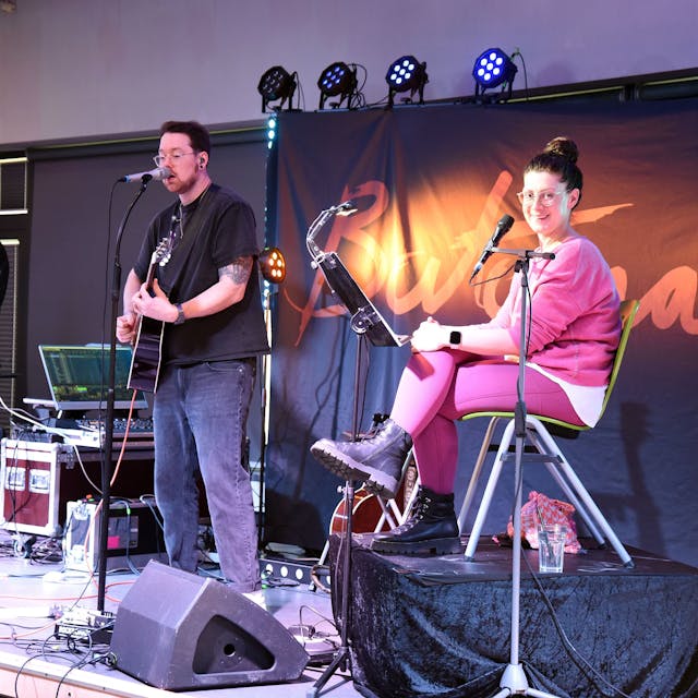 Bloggerin Jana Craemer (links) und die Musiker von Bartomae auf der Bühne im Aggertal-Gymnasium in Engelskirchen.