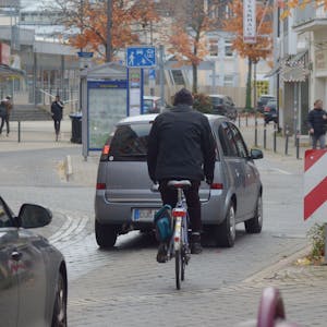 Das Bild zeigt einen Radfahrer in der Euskirchener Innenstadt. Vor und hinter ihm fahren Autos.