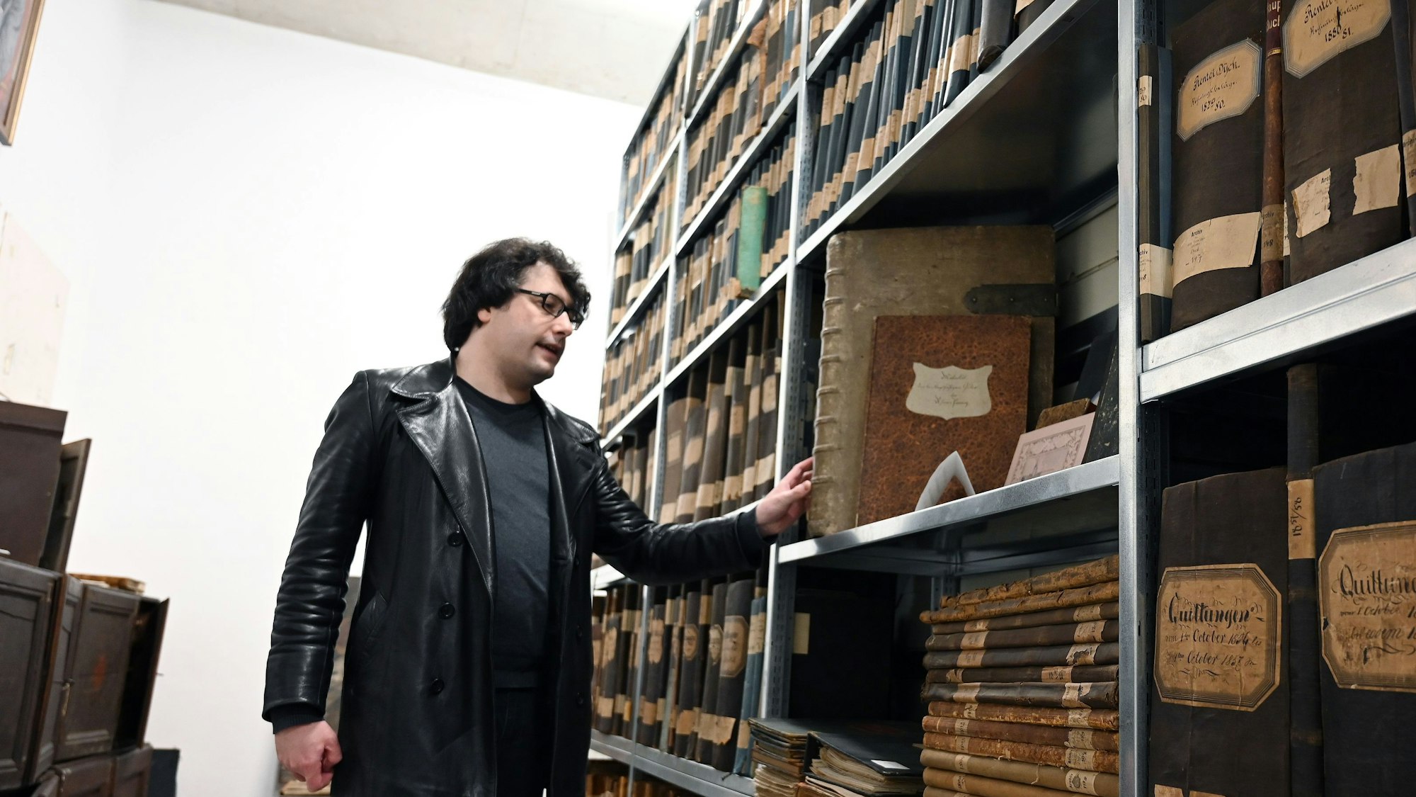Juliano de Assis Mendonça zeigt im Depot der Vereinigten Adelsarchive im Rheinland ein Buch aus dem 18. Jahrhundert.