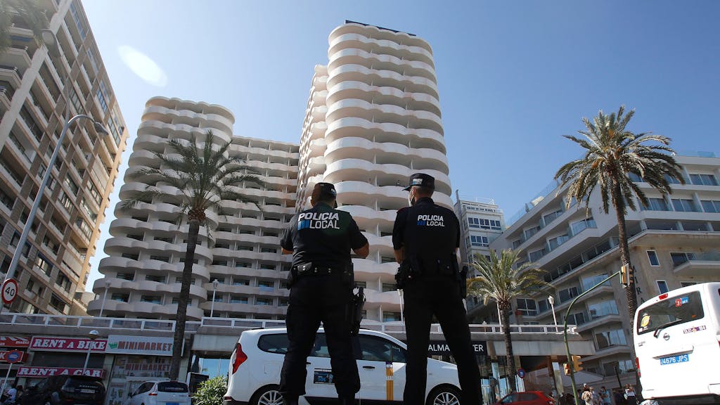 Zwei Polizisten stehen im Einsatz vor dem Hotel auf Mallorca, in dem mehr als 200 Schülerinnen und Schüler in Corona-Zwangsquarantäne gesetzt wurden.