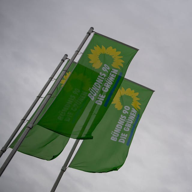 Flaggen mit dem Logo von Bündnis 90/Die Grünen wehen an Fahnenmasten. Im baden-württembergischen Amtzell ist ein 37-Jähriger offenbar attackiert worden, weil er für die Grünen kandidieren will. (Symbolbild)