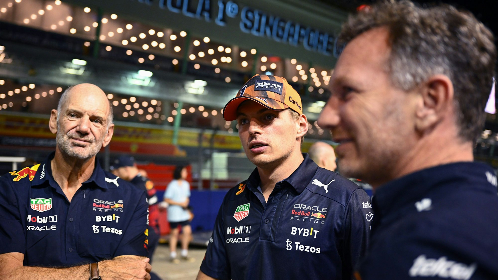 Red-Bull-Designer Adrian Newey (l.), Max Verstappen (M.) und Teamchef Christian Horner stehen nebeneinander in der Boxengasse.