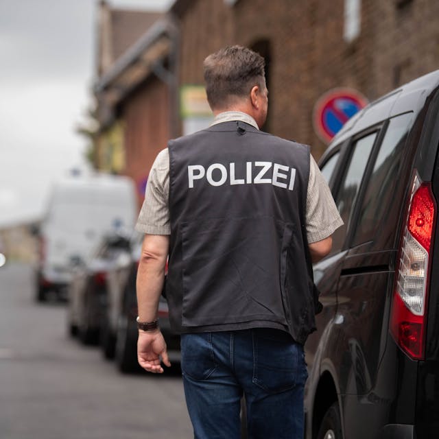 Nach einem brutalen Überfall in Zülpich-Füssenich geht ein Ermittler, der eine Weste mit der Aufschrift „Polizei“ trägt, zu einem Haus.