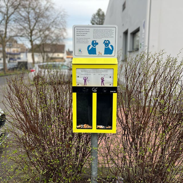 Ein gelber Sammelbehälter für Zigarettenkippen mit zwei Fächern.