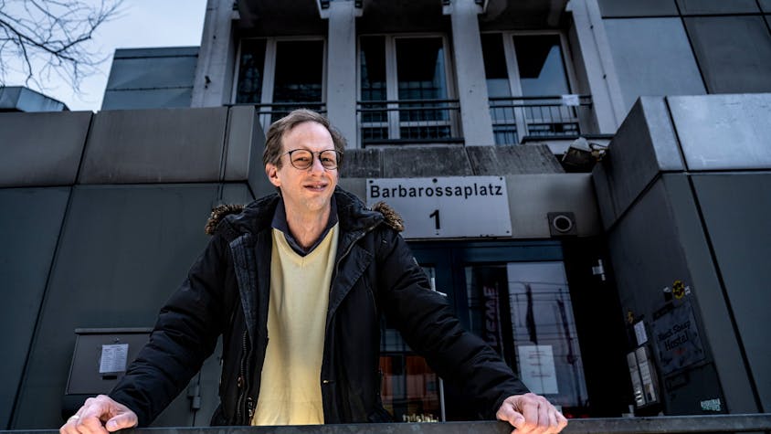 Regisseur Malte Wirtz stützt sich vor dem Haus am Barbarossaplatz 1 auf einen Zaun.