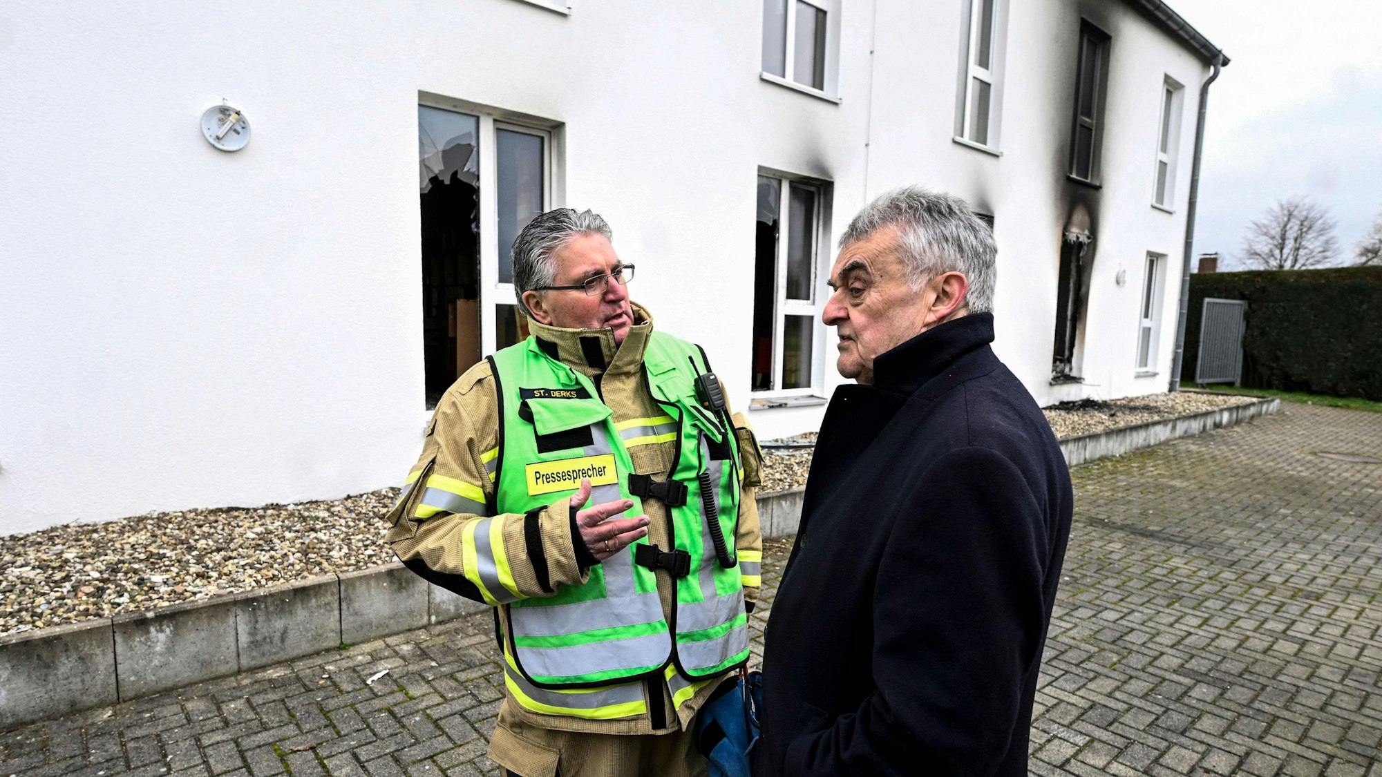 NRW-Innenminister Herbert Reul (CDU) im Gespräch mit einem Feuerwehr-Sprecher an der Seniorenunterkunft.