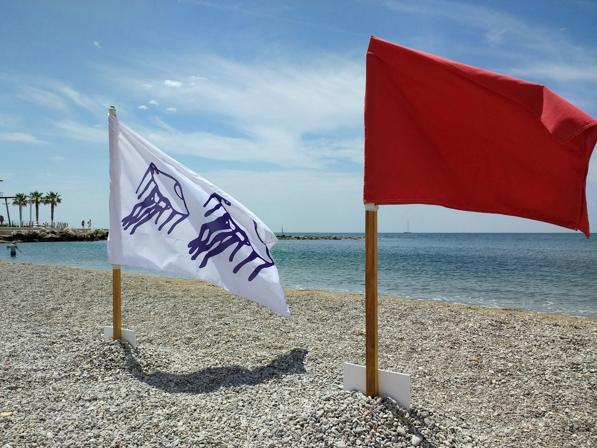 Eine rote Flagge und eine Flagge mit stilisierten Quallen sind am Strand gehisst. Quallen halten Menschen auf Mallorca und anderswo in Spanien immer mal wieder vom Wasser fern. Das Foto wurde bereits 2018 in El Molinar auf Mallorca aufgenommen.