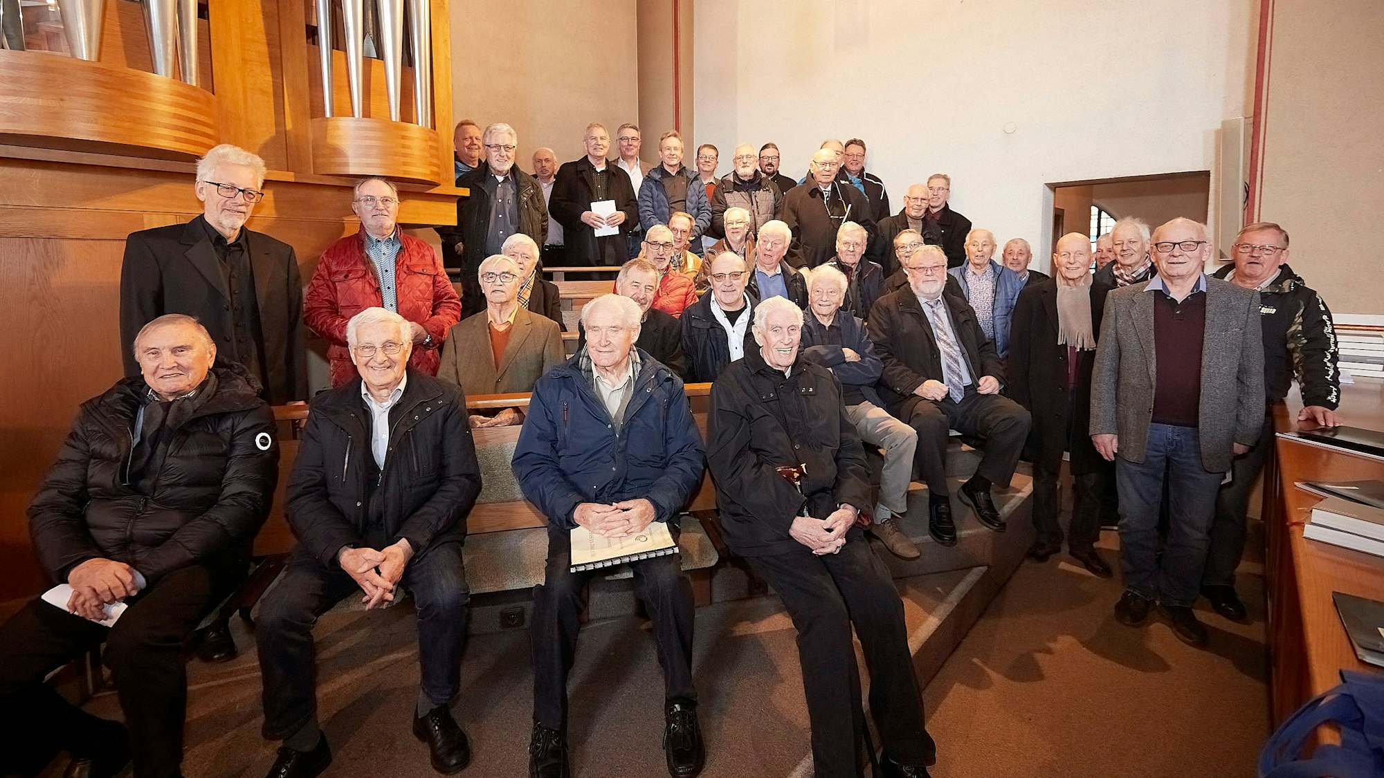 Zahlreiche Sänger von Männergesangvereinen stehen und sitzen an einer Kirchenorgel.