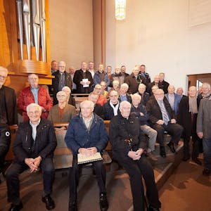 Zahlreiche Sänger von Männergesangvereinen stehen und sitzen an einer Kirchenorgel.