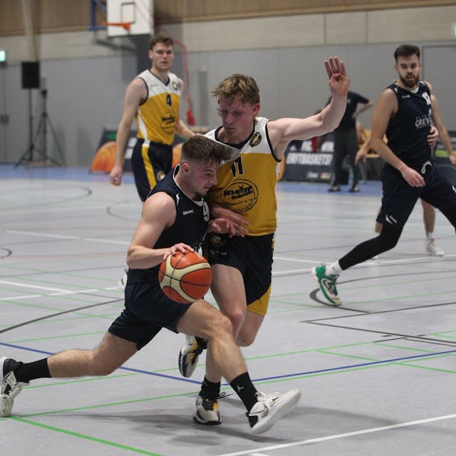 Jan Züll hält mit dem linken Arm einen Gegner von sich fern, mit dem rechten führt er den Ball.