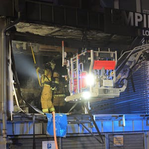 Feuerwehrleute arbeiten in einem ausgebrannten Ladenlokal.