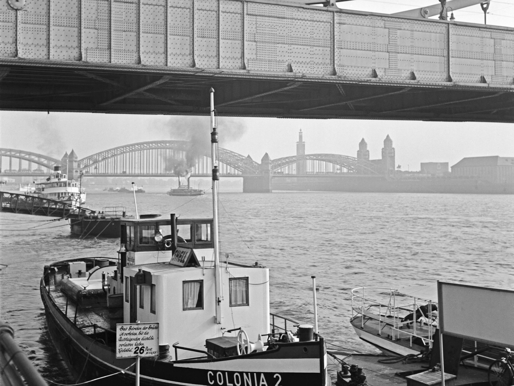 Im Vordergrund die Hindenburgbrücke – sie brach am 28. Februar 1945 zusammen – an der Stelle wurde die Deutzer Brücke errichtet. Im Hintergrund ist die Hohenzollernbrücke zu sehen.